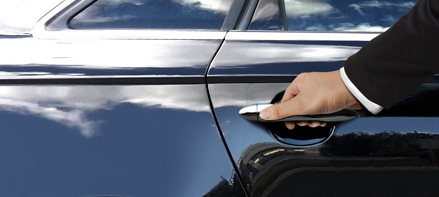 Man in suit opening a black car door